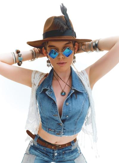 Peace & Love Denim Rebel Крупний план: укорочений джинсовий жилет на ґудзиках, біла мереживна накидка, окуляри-ромби з блакитними лінзами й кулон