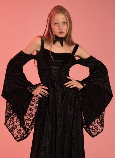 Velvet Sorceress Ritual Готична відьма в чорній оксамитовій сукні з відкритими плечима, руки на талії, рожеве тло