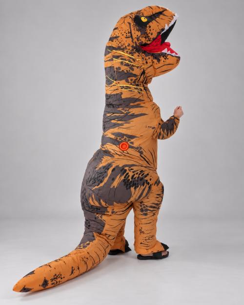 T-Rex зі спини на три чверті: темна луска на стегнах, кругла помаранчева кнопка збоку, хвіст по підлозі